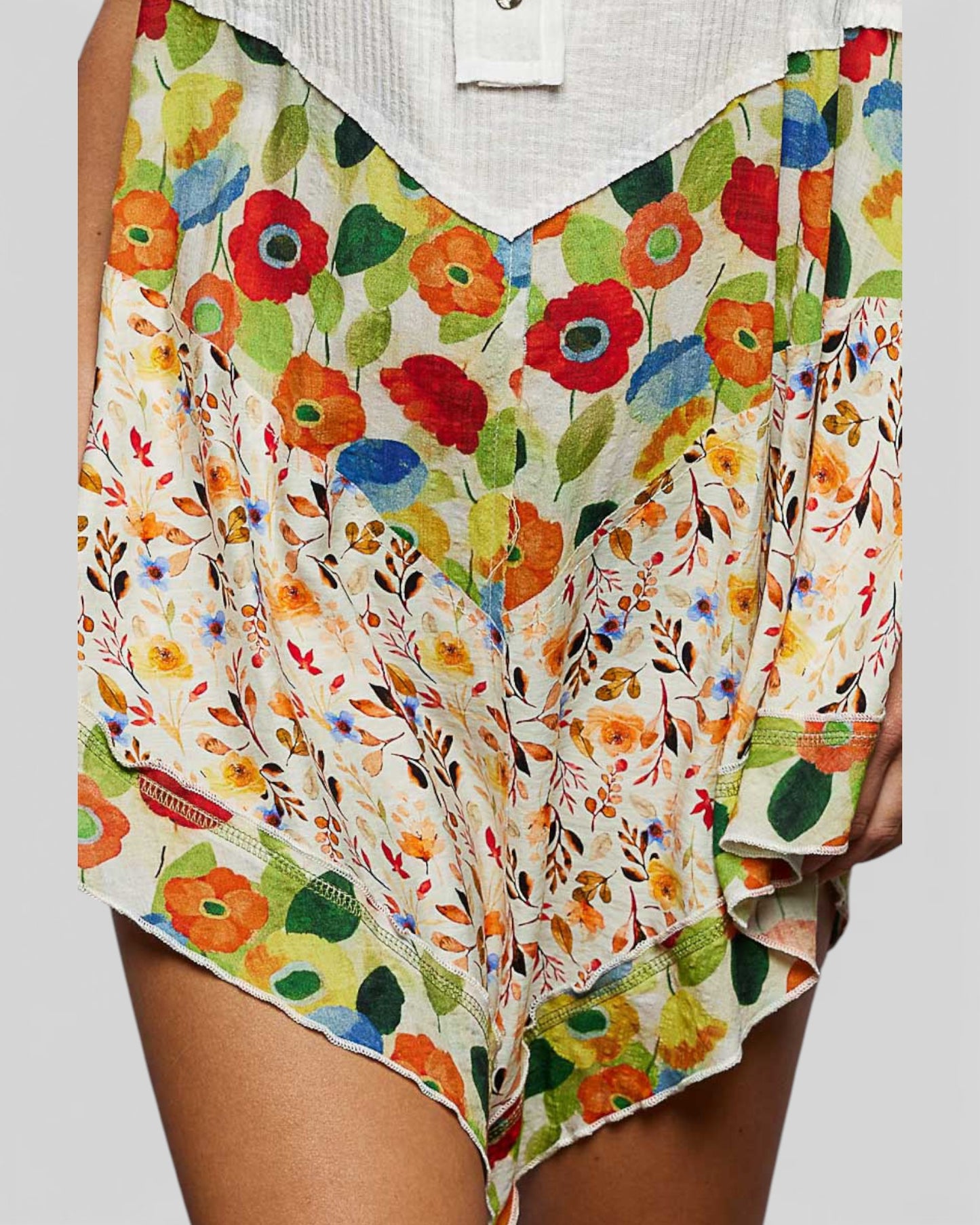 Colorful floral-patterned garment held by a person on a plain background