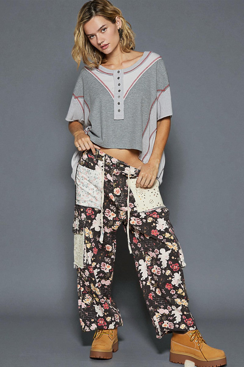 Woman wearing a casual outfit with a gray top and floral pants against a gray background