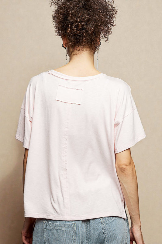 Person wearing a white t-shirt and blue jeans against a beige background