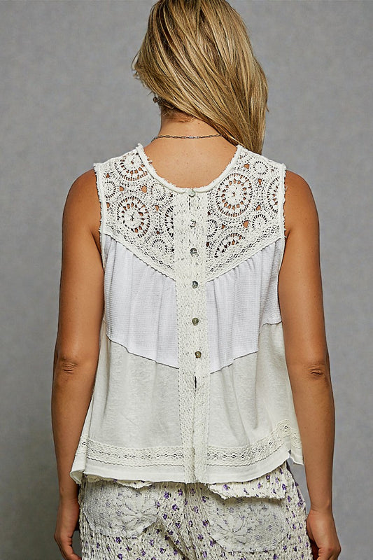 Woman wearing a layered outfit with a white lace top and floral pants against a gray background