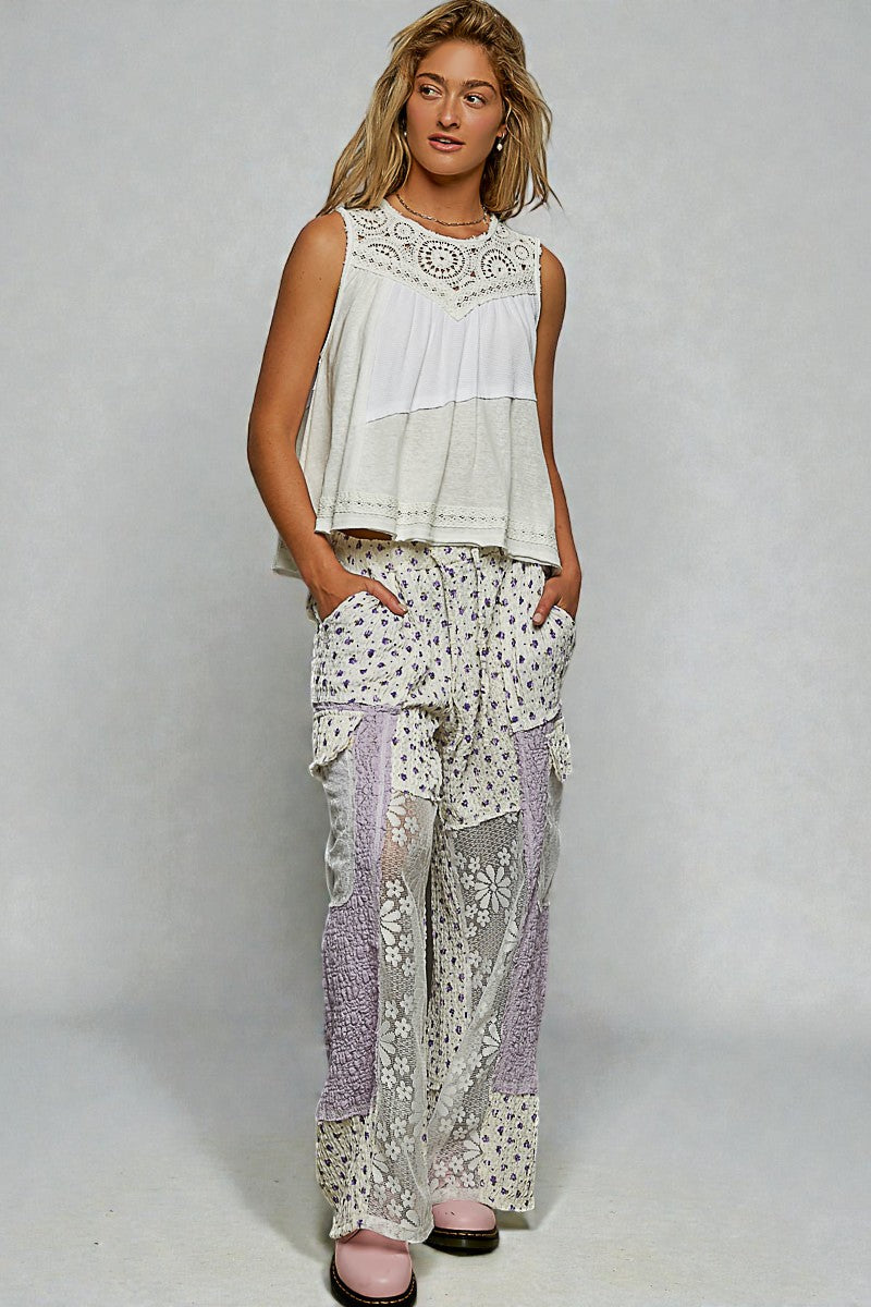 Woman wearing a white sleeveless top and patterned pants on a gray background