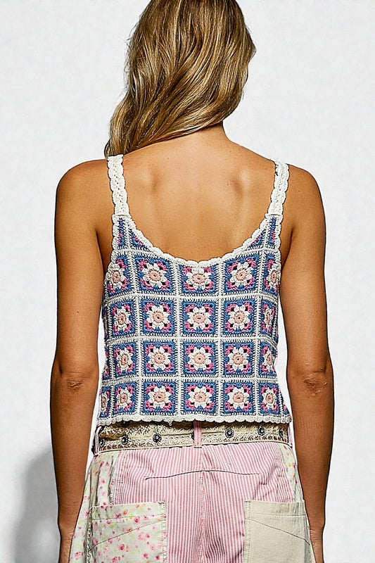 Person wearing a colorful crochet tank top with a white background