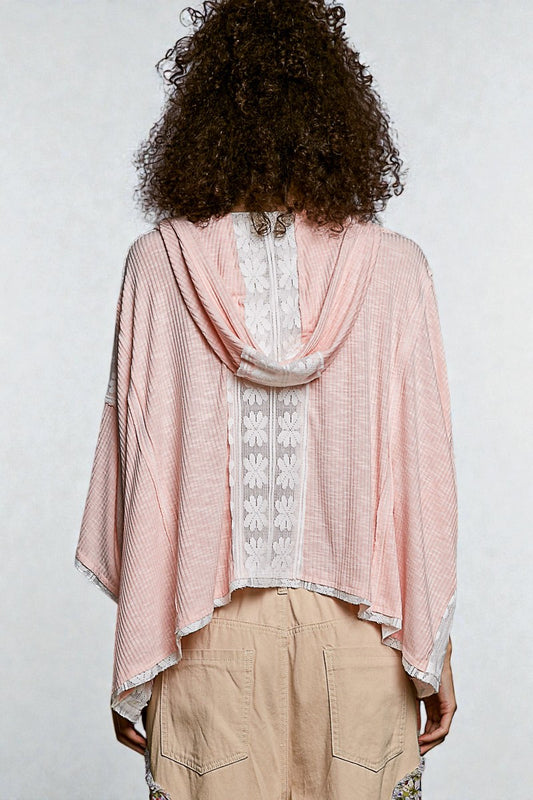 Person wearing a pink and white patterned top with beige pants on a plain background