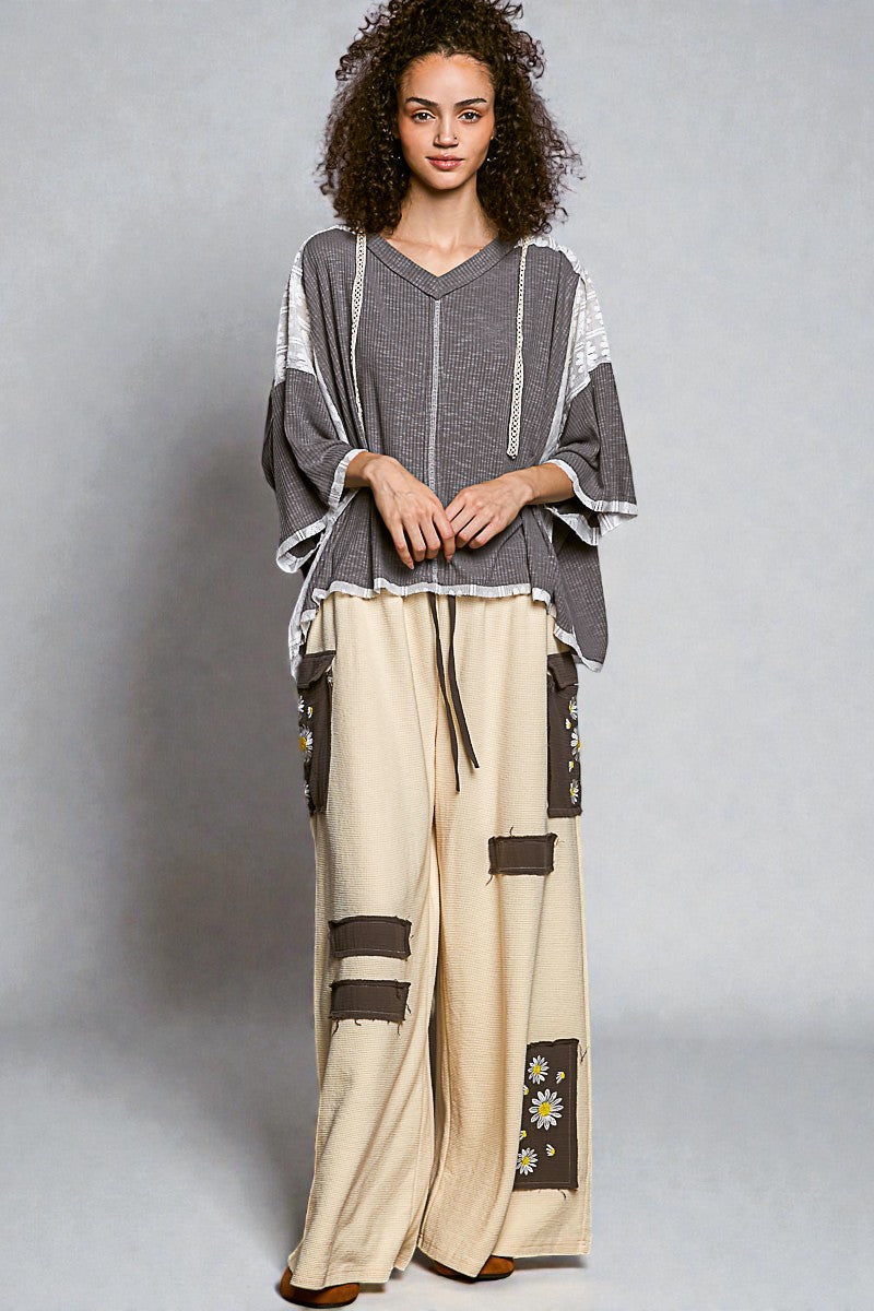 Woman wearing a gray top and beige pants with black and white patterns on a gray background