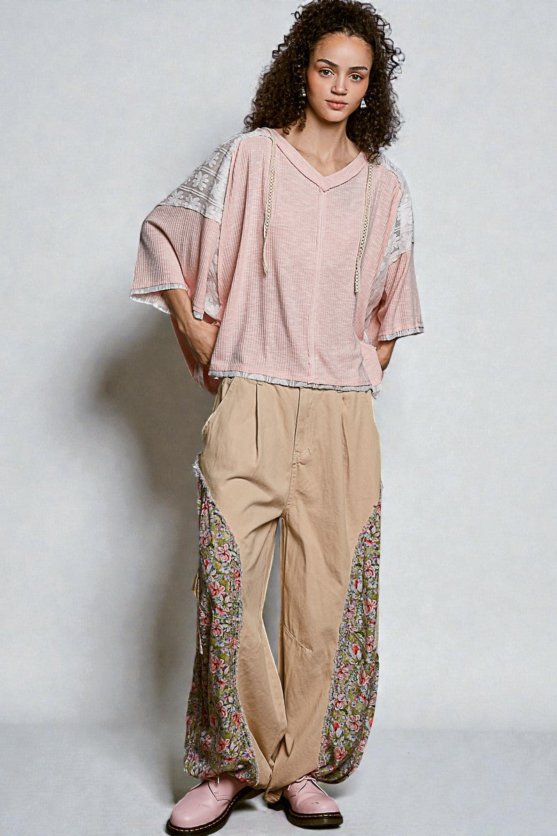 Woman wearing a pink top and beige pants with floral patterns on a white background