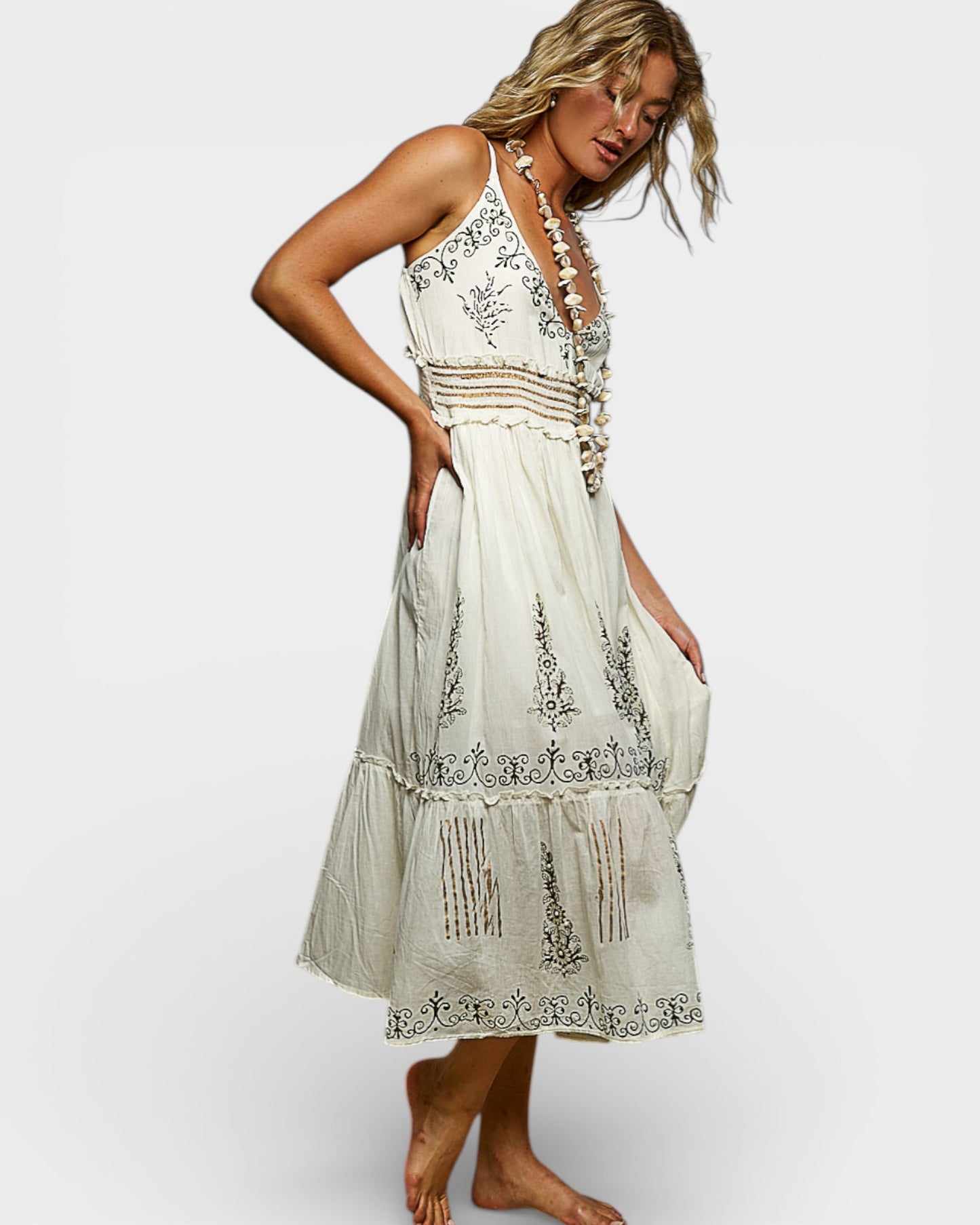 Woman wearing a white embroidered dress on a plain background