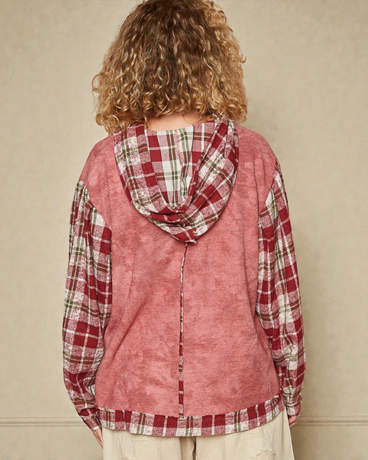Person wearing a red plaid shirt with a hood against a beige background