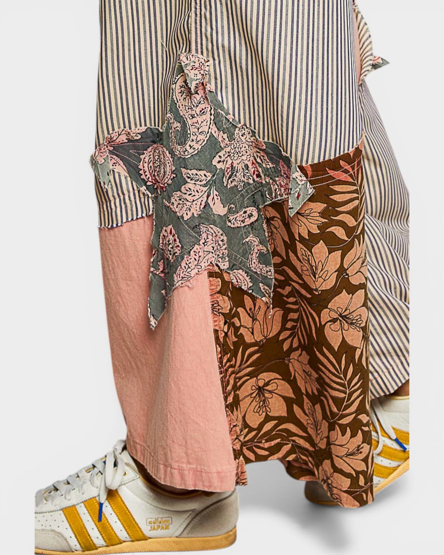 Person wearing a striped shirt with floral and animal print pants on a light gray background