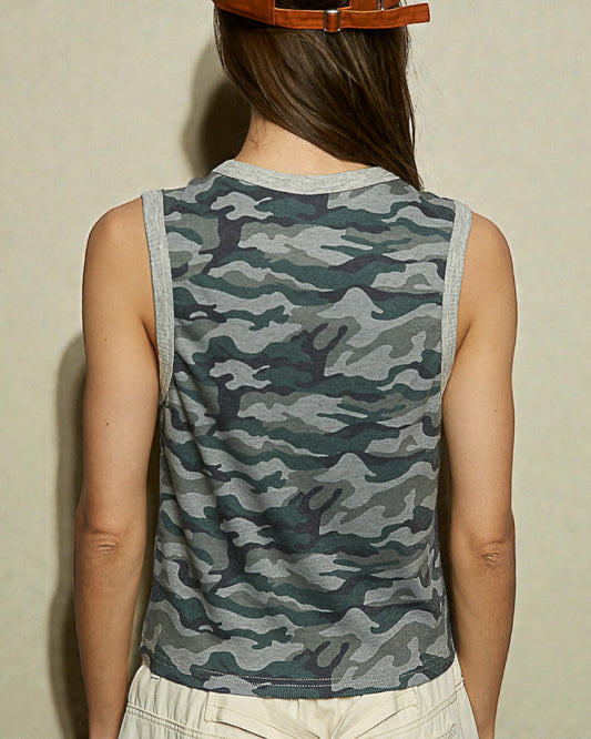 Person wearing a camouflage sleeveless shirt against a neutral background
