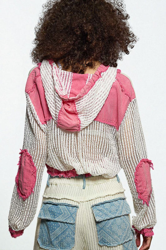 Person wearing a pink and white jacket with a textured pattern on a plain background