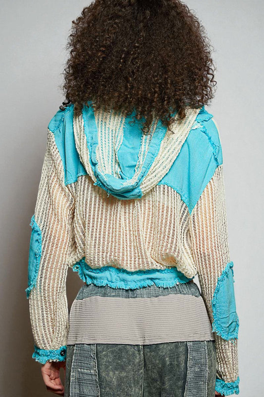 Person wearing a textured sweater with blue accents on a plain background