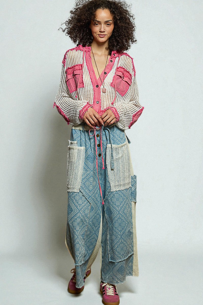 Woman wearing a colorful outfit with a pink and white top and blue patterned pants on a plain background