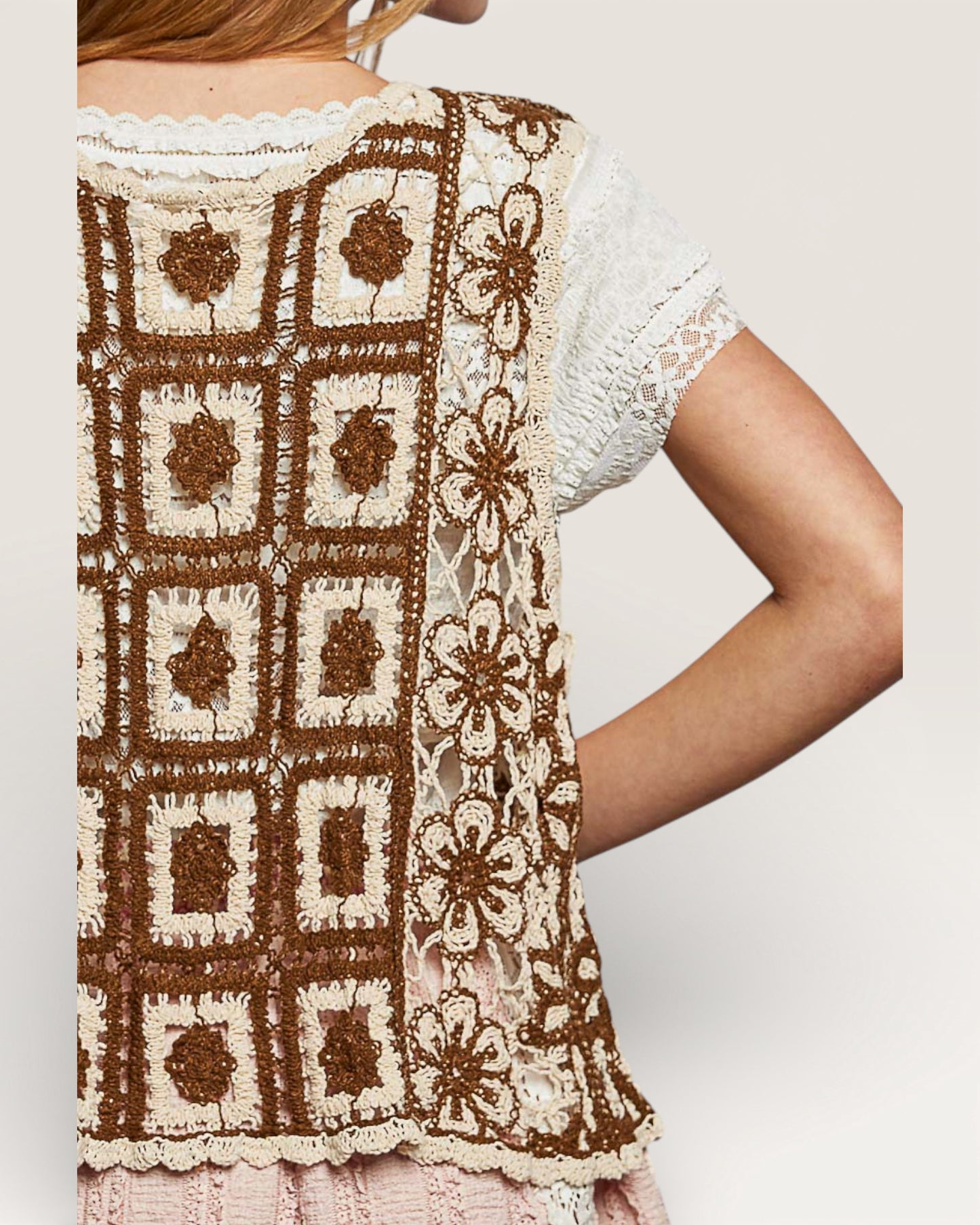 Close-up of a person wearing a brown and white patterned top with a plain background