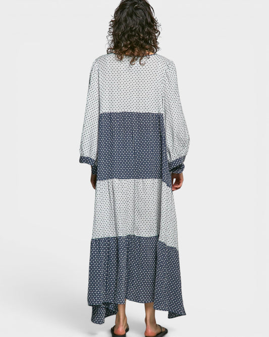 Woman wearing a long, patterned dress with a white background
