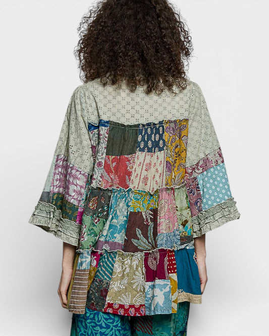 Person wearing a colorful patchwork kimono-style garment on a white background