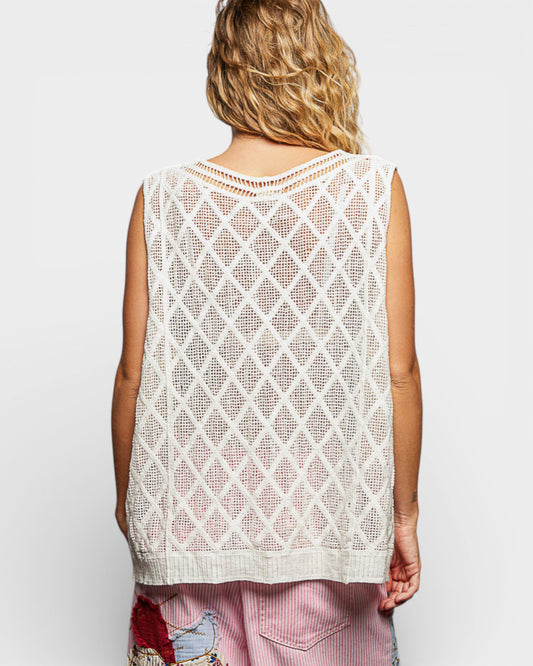 Person wearing a white mesh sleeveless top on a plain background