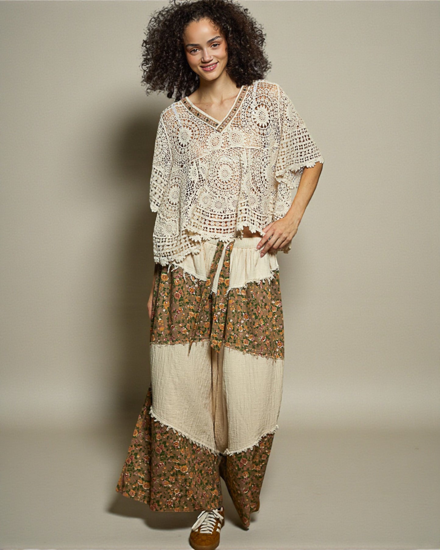 Woman wearing a bohemian-style outfit with a patterned top and skirt on a plain background