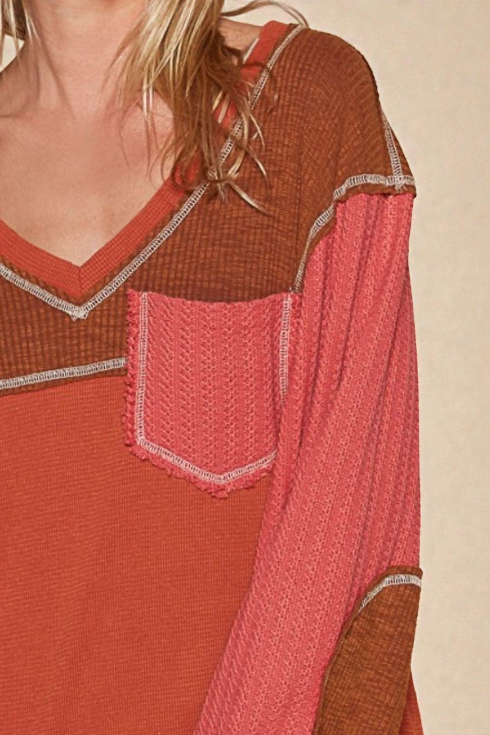 Long-sleeve top with a pocket in shades of red and brown on a beige background