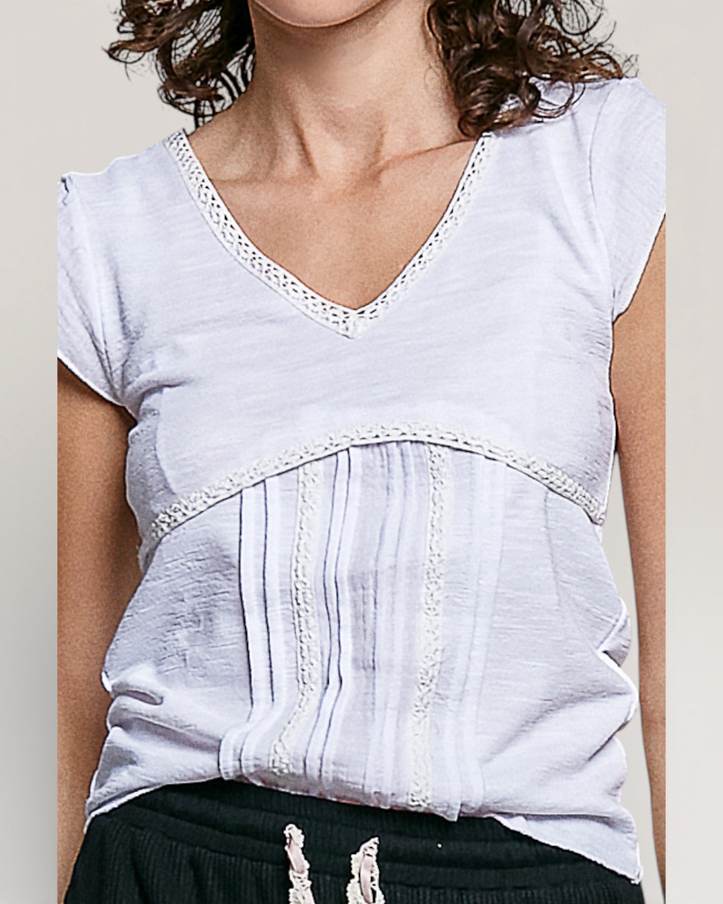 White blouse with lace details worn by a person on a plain background