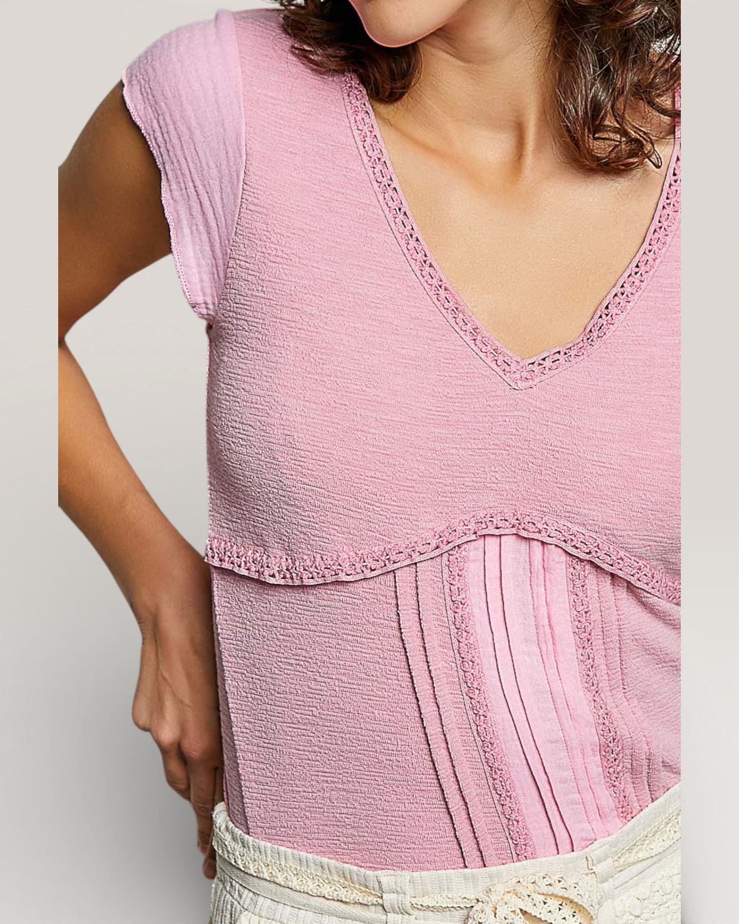 Close-up of a pink sleeveless top with lace details on a plain background
