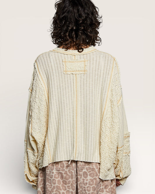 Person wearing a textured beige shirt with a plain background