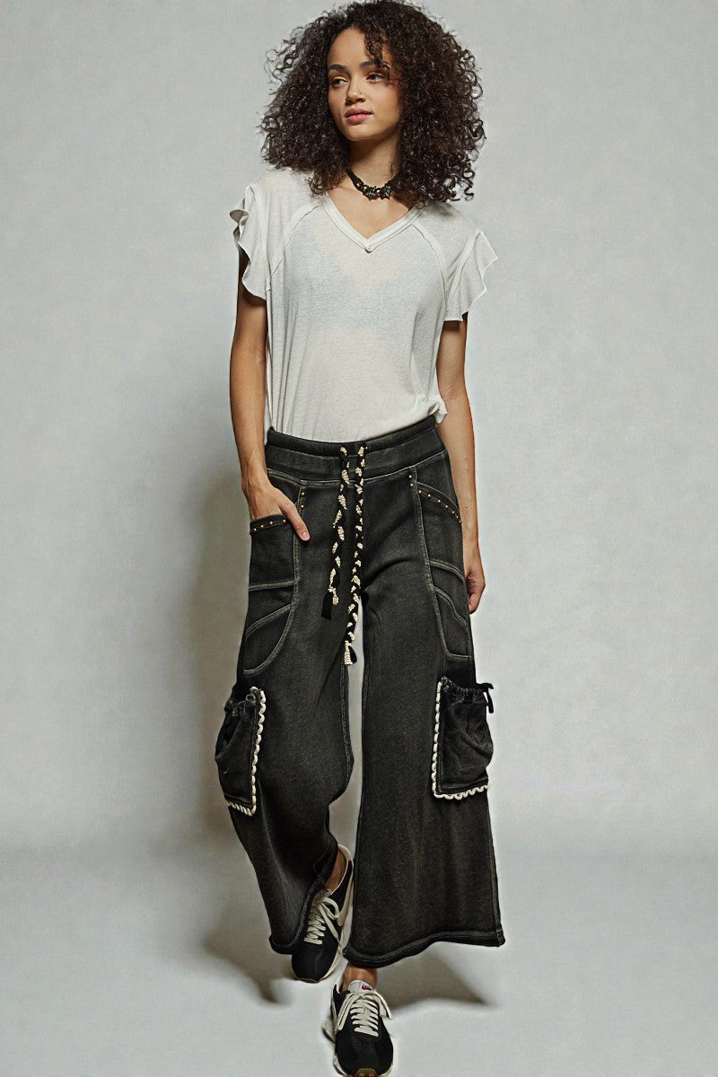 Woman wearing a white top and dark cargo pants against a plain background