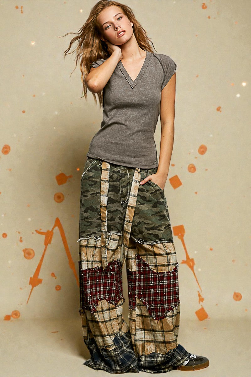 Woman wearing a gray top and plaid patchwork pants against a beige background