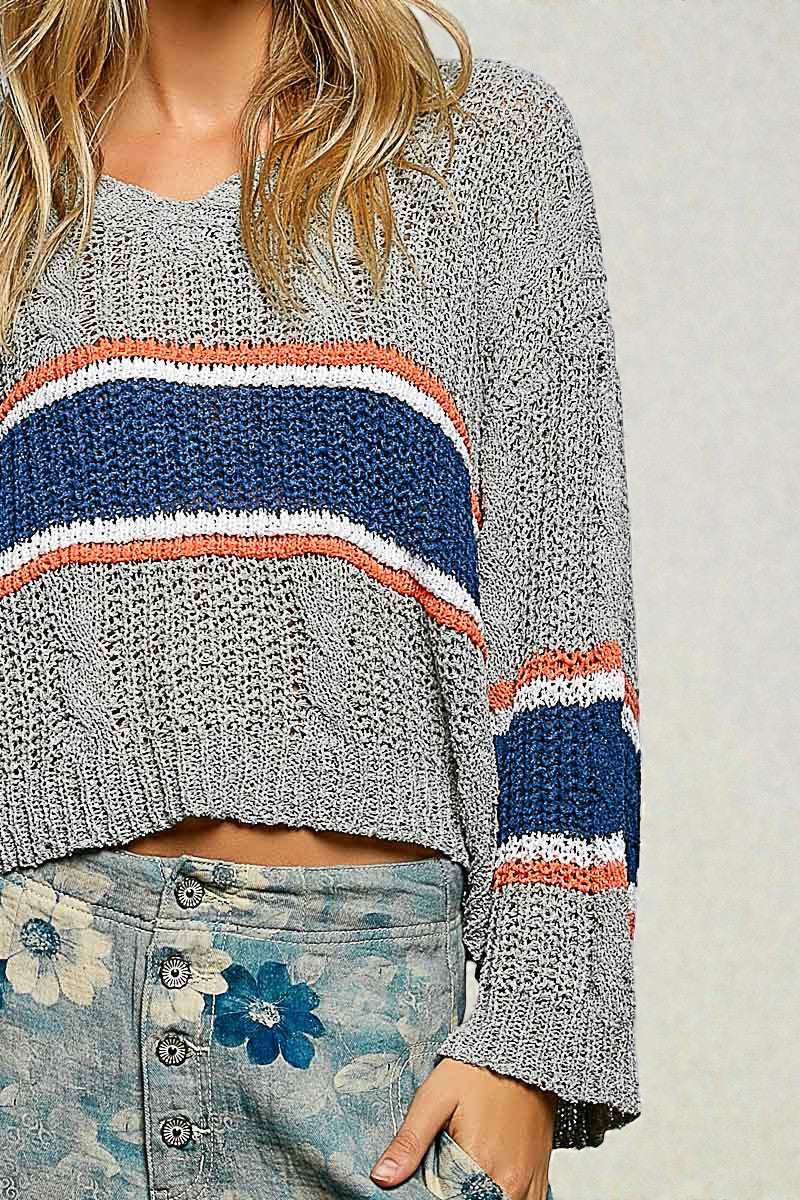 Gray sweater with colorful stripes worn by a person, with a neutral background