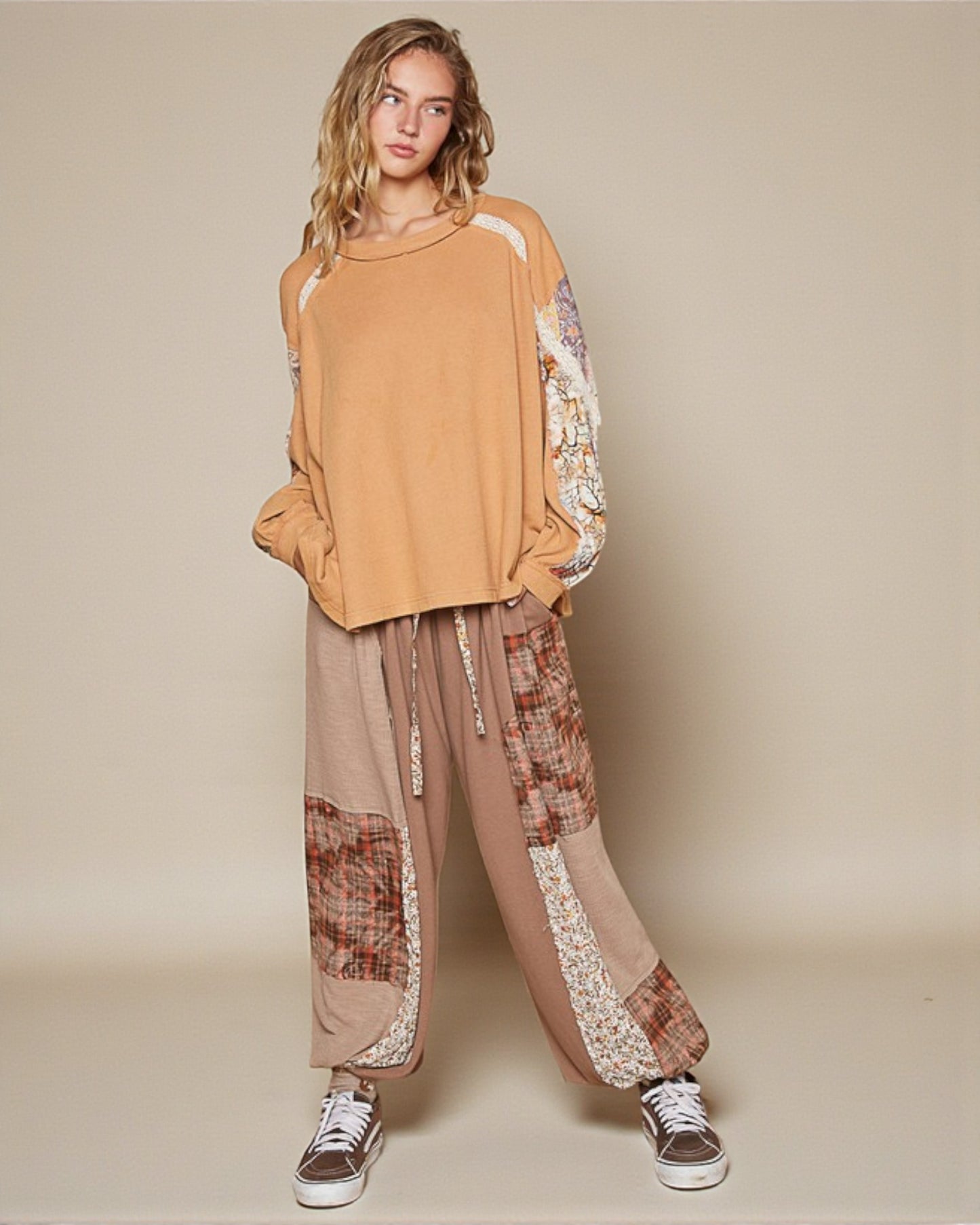 Person wearing a mustard yellow top and patterned pants on a beige background