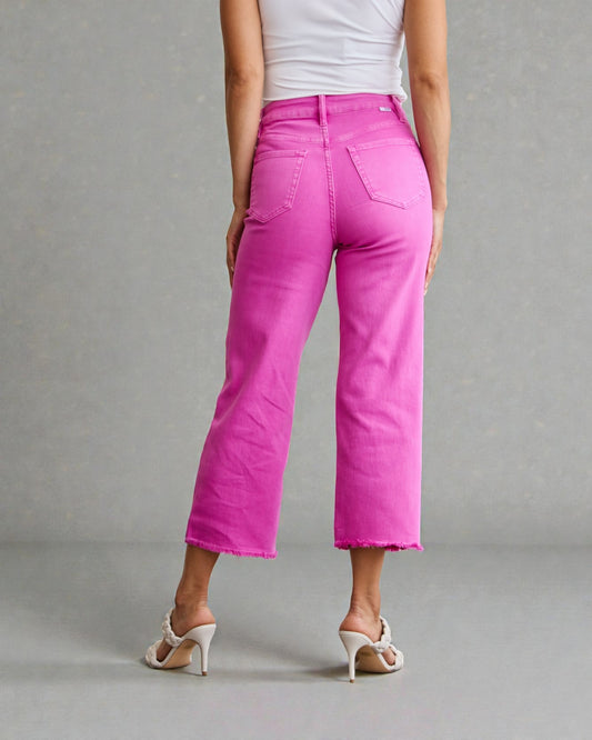 Person wearing bright pink pants and a white top on a gray background