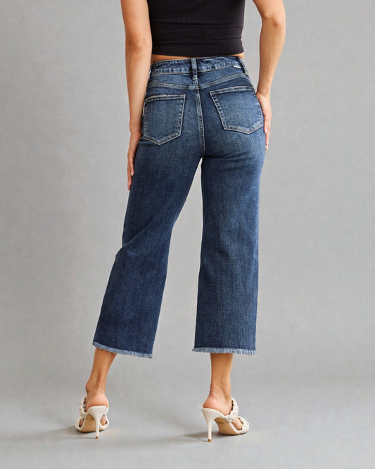 Person wearing blue jeans and a black top on a gray background