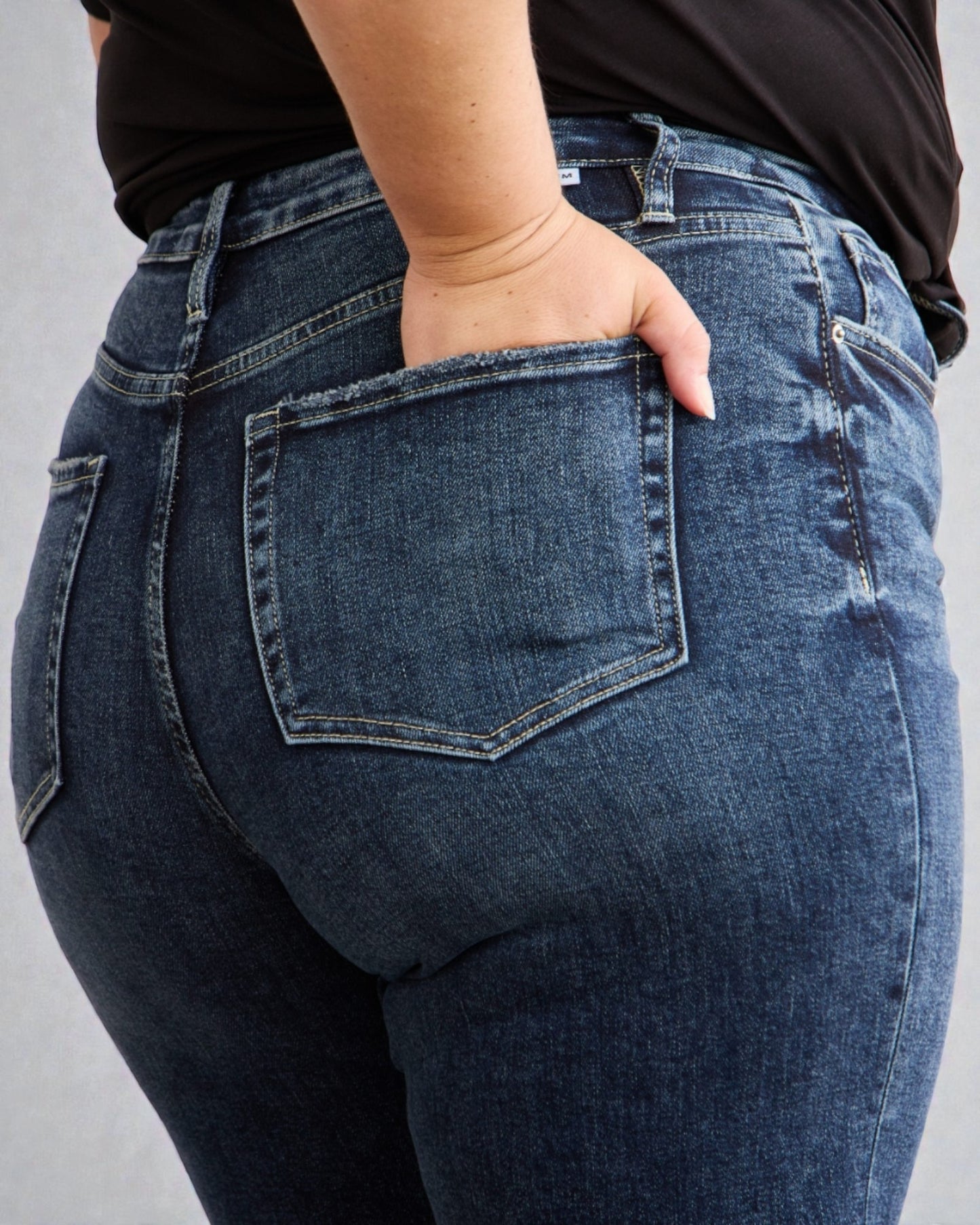 Person wearing blue jeans with a plain background