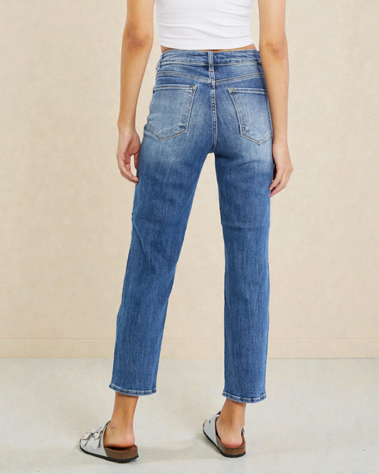 Person wearing blue jeans and a white top on a beige background