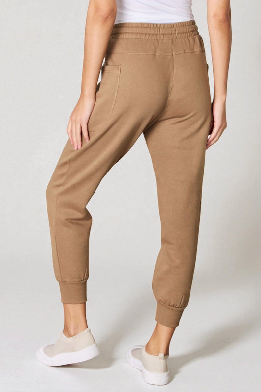 Person wearing tan jogger pants on a white background