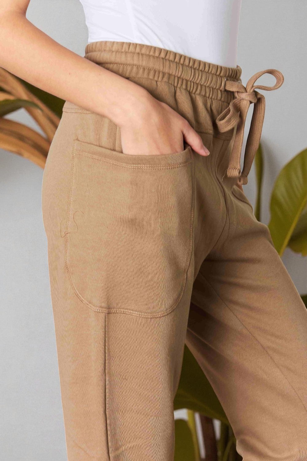 Tan pants with a drawstring waist worn by a person, against a neutral background.