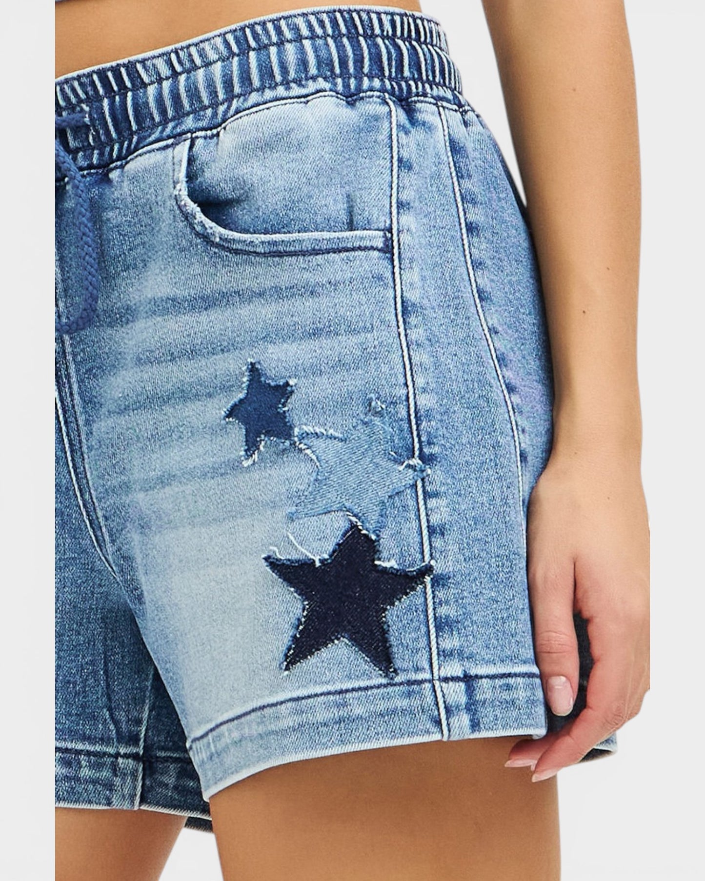 Blue denim shorts with star patches on a white background