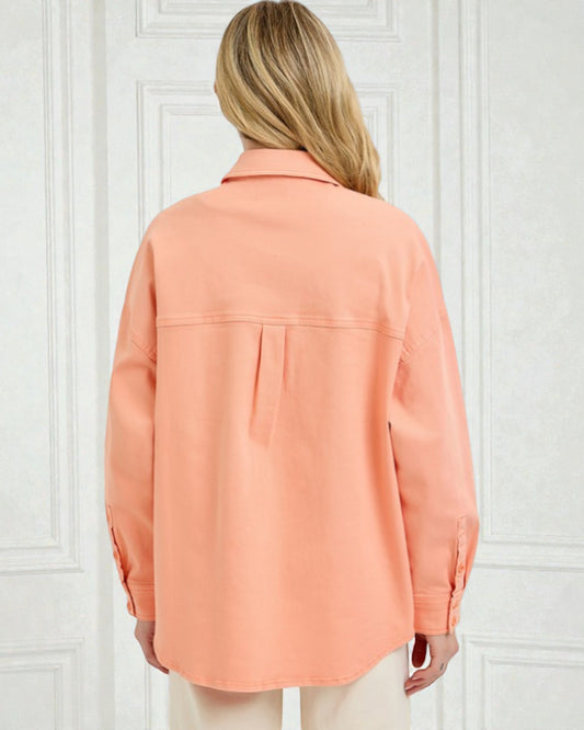 Person wearing a peach-colored shirt against a white paneled wall