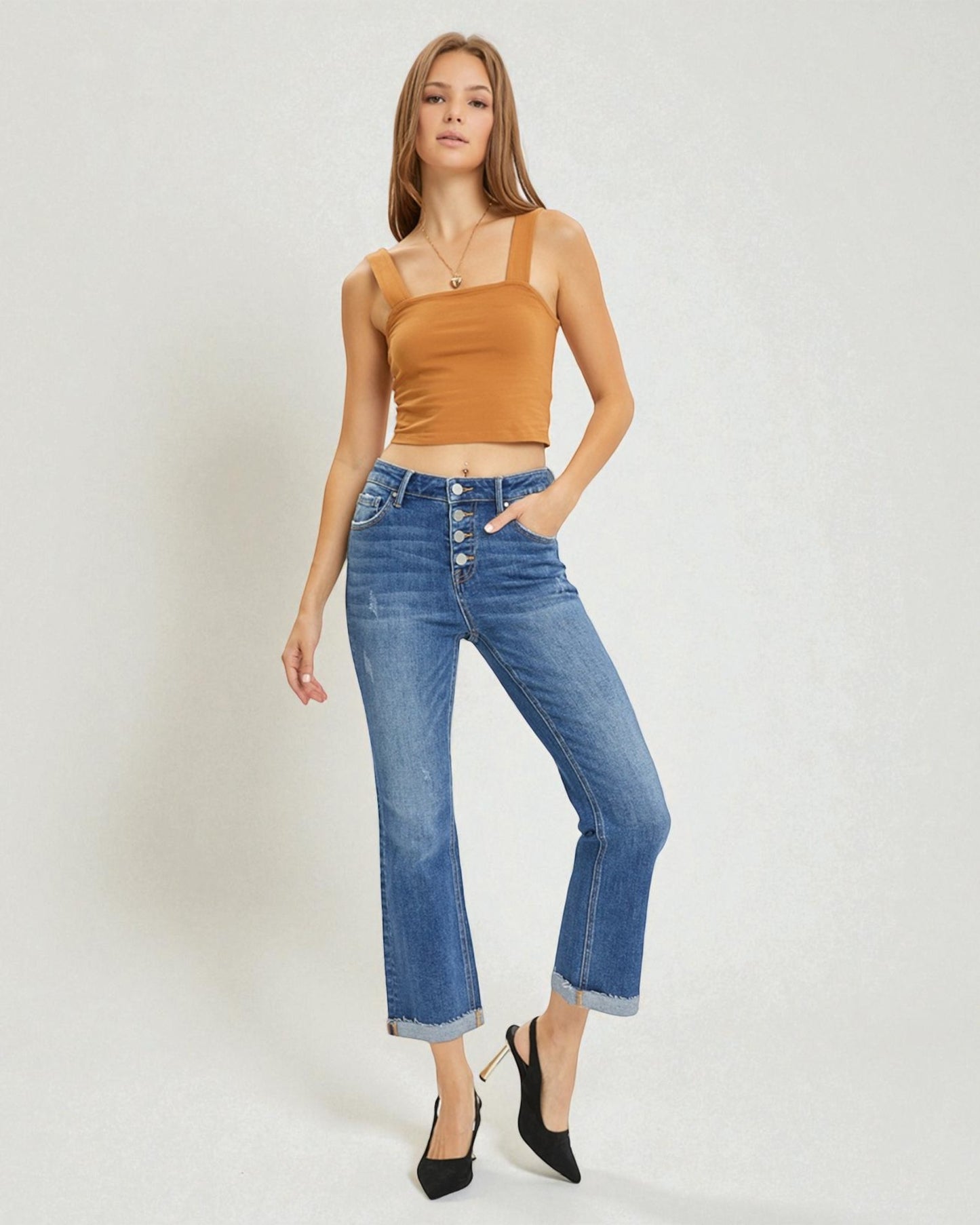 Woman wearing a mustard yellow top and blue jeans on a white background