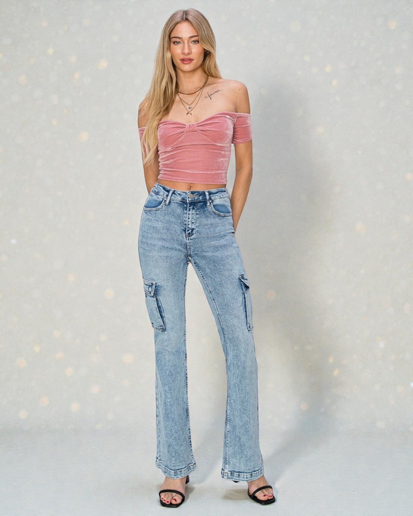 Woman wearing a pink top and blue jeans against a light gray background