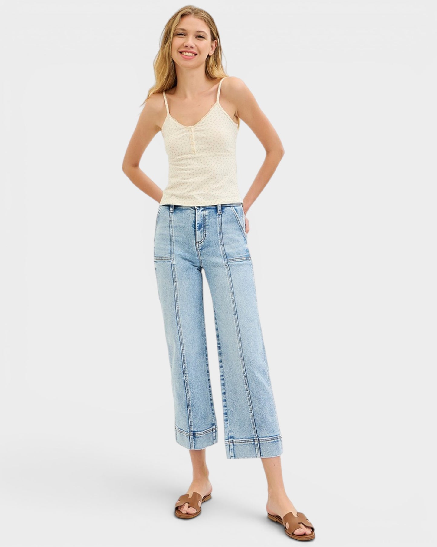 Woman wearing a white tank top and light blue jeans on a white background