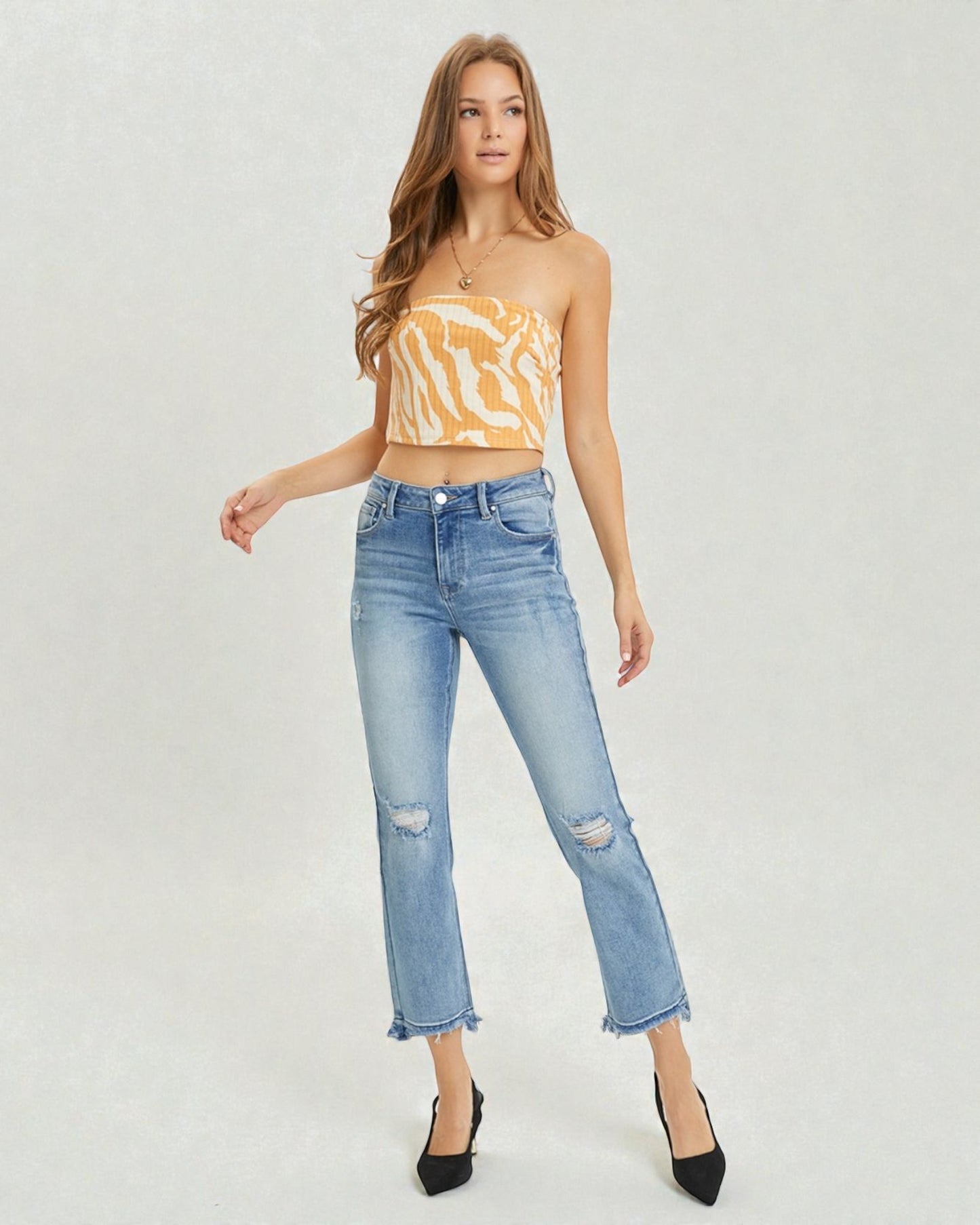Woman wearing a yellow strapless top and light blue jeans on a white background