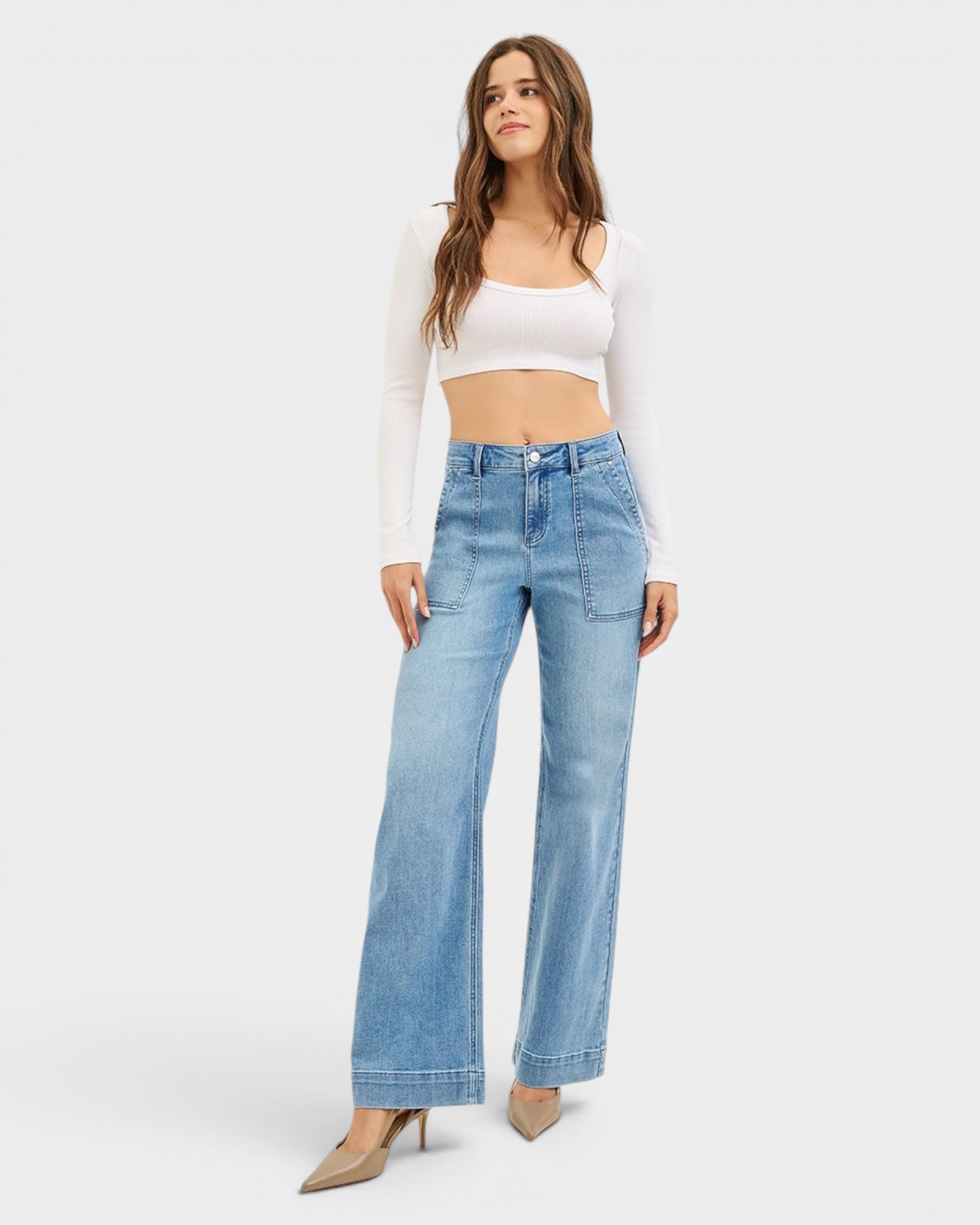 Woman wearing light blue jeans and a white top on a white background