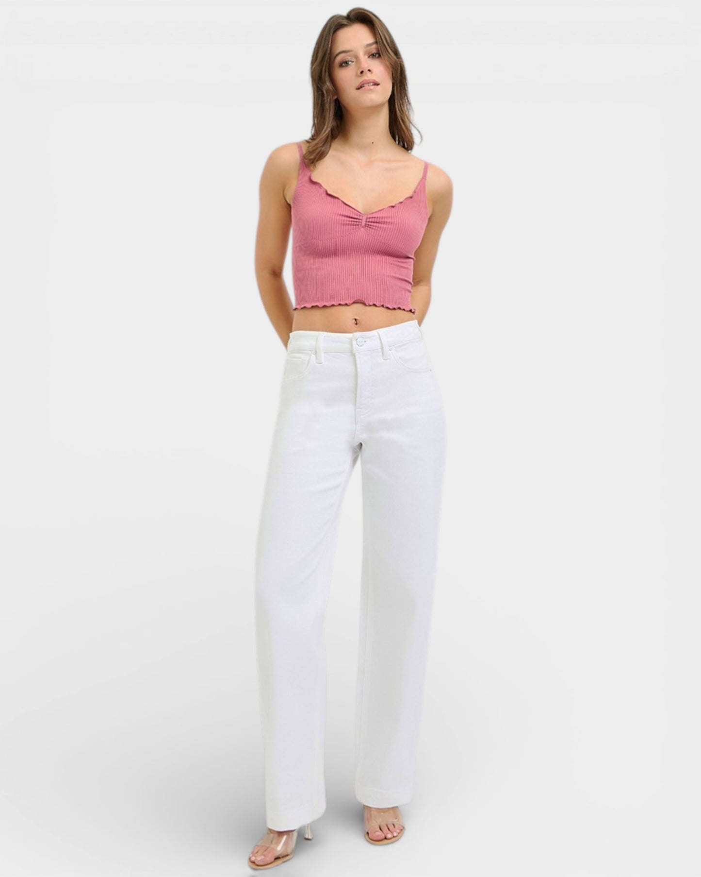 Woman wearing a pink top and white pants on a white background