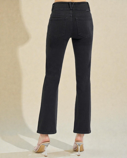 Black jeans worn by a person on a beige background
