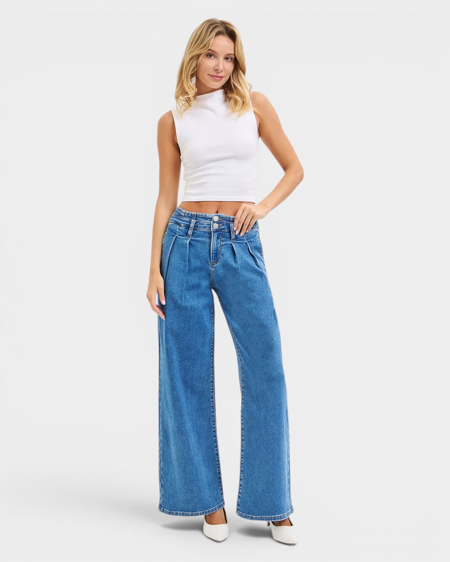Woman wearing a white sleeveless top and blue jeans on a white background