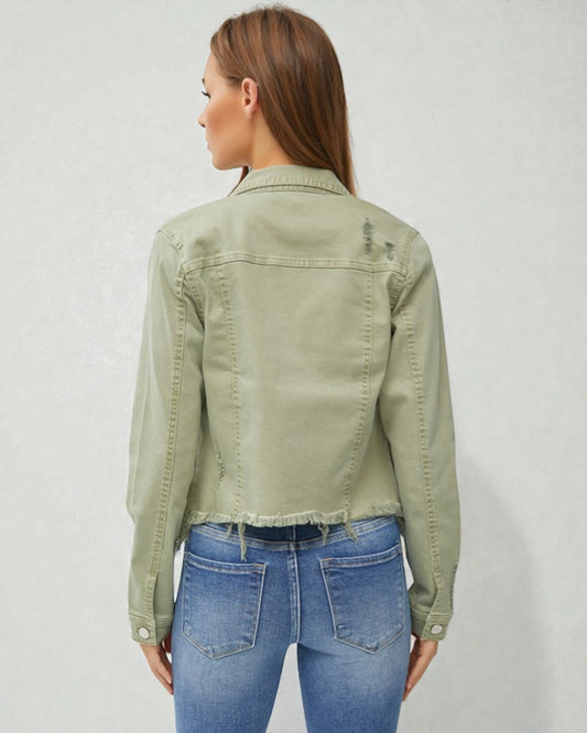 Woman wearing a green denim jacket and blue jeans on a plain background