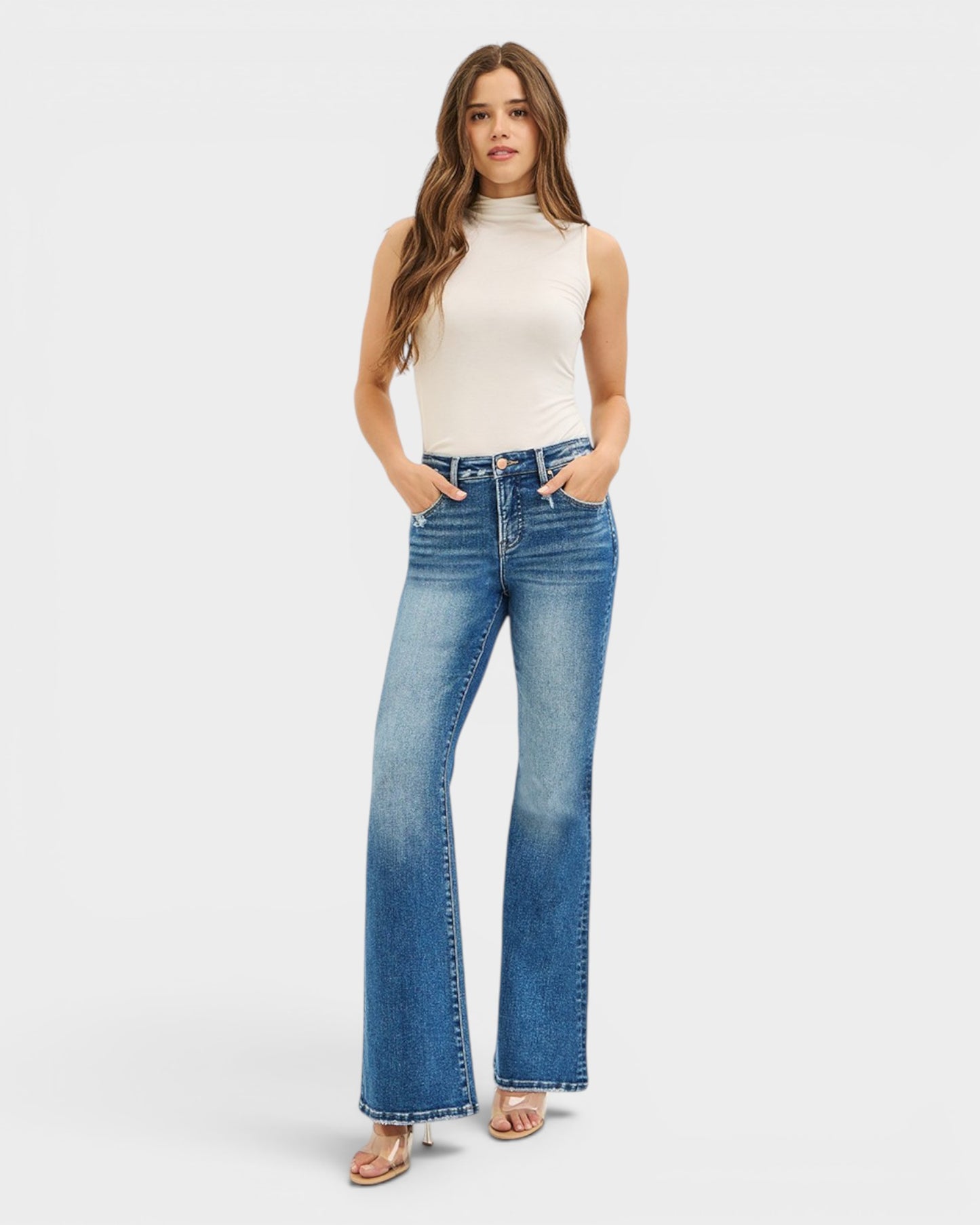 Woman wearing blue jeans and a white top on a white background