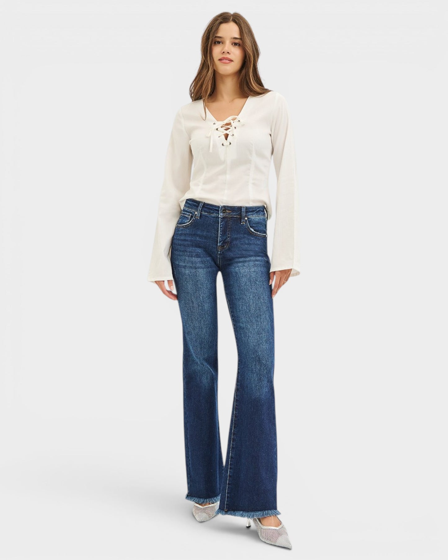 Woman wearing a white blouse and blue jeans on a white background