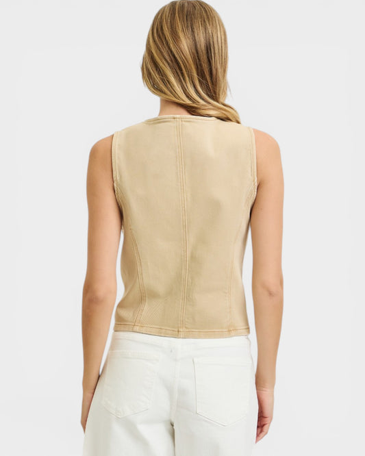 Woman wearing a beige sleeveless top against a white background