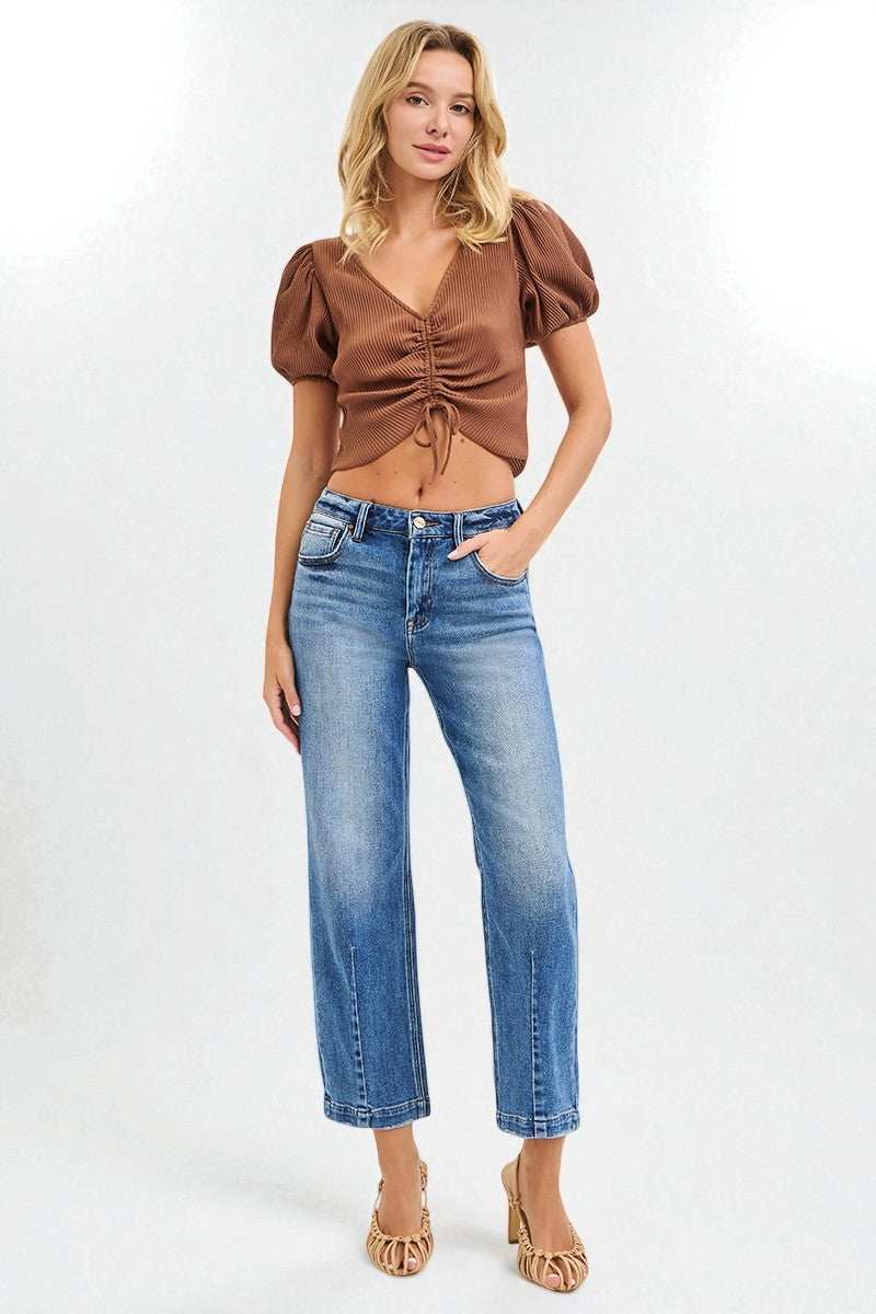 Woman wearing a brown top and blue jeans on a white background
